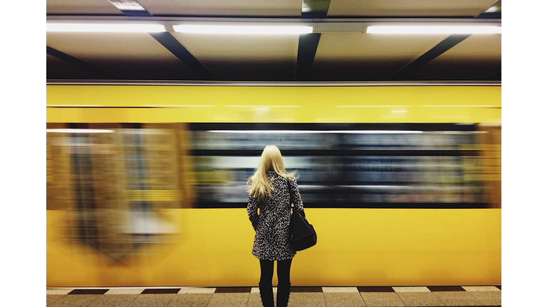 Rear View Of Woman Standing By Moving Train At Subway Station