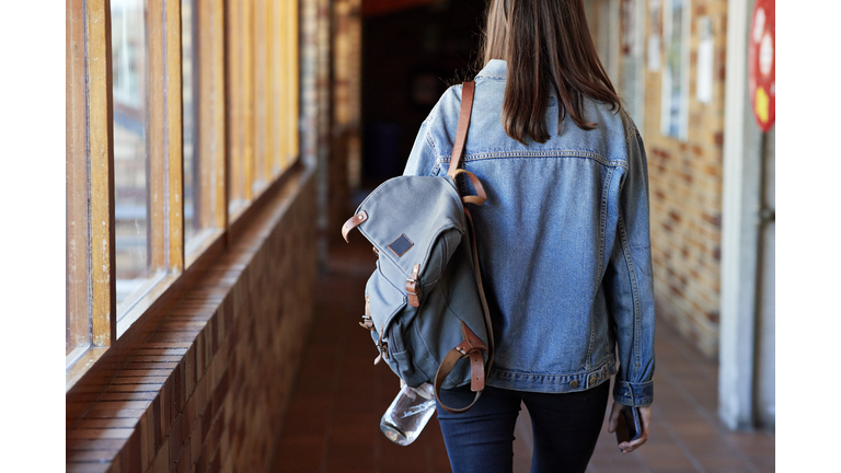 Young woman with backpack walking in corridor