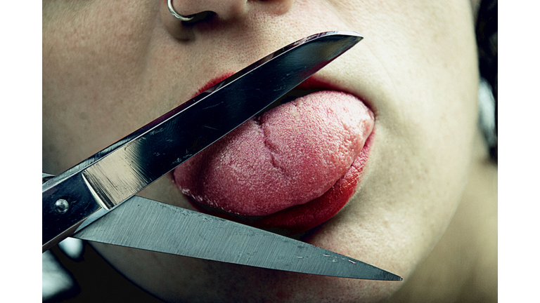 Close-up of a woman cutting her tongue with scissors