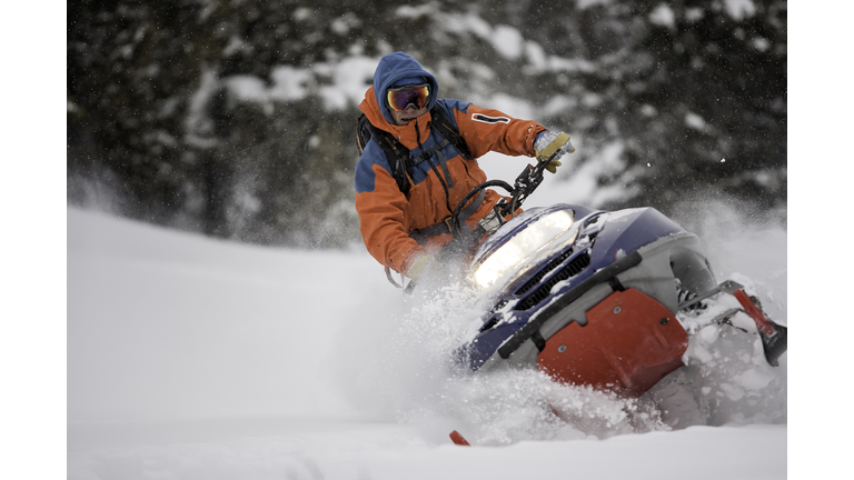 Guy on a snowmobile taking a powder turn.