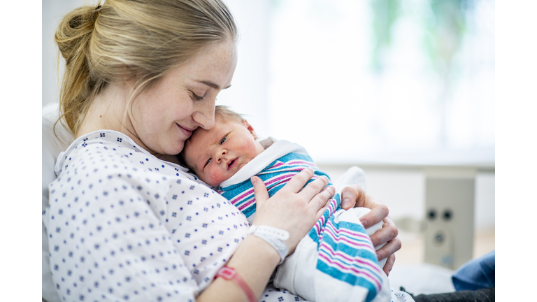 New mom holds her baby in hospital bed