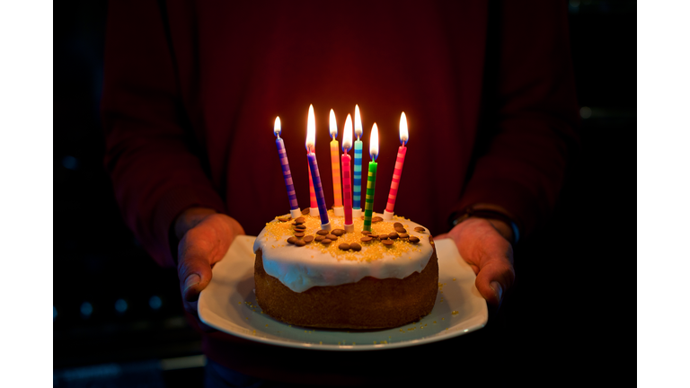 Man, birthday cake, 8 glowing coloured candles