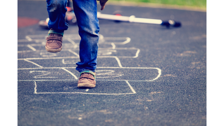 kid playing hopscotch on playground outdoors