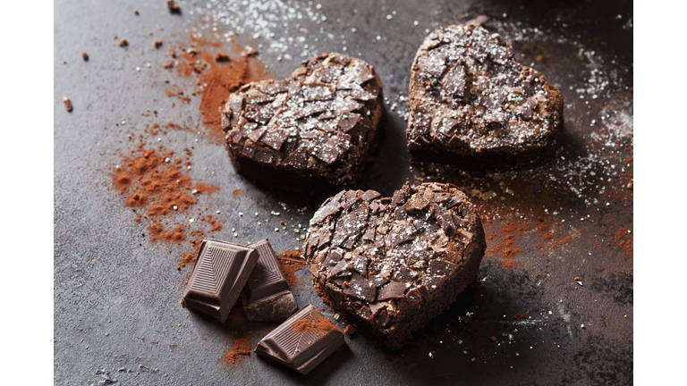 Three heart-shaped brownies and chocolate on metal