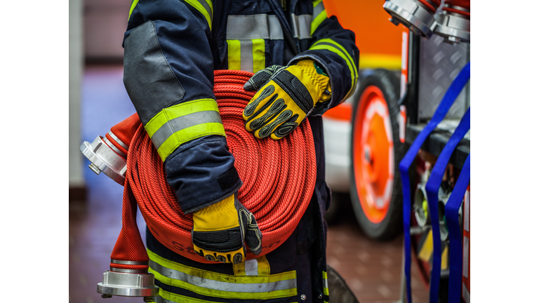 Midsection Of Firefighter Holding Hose At Fire Station