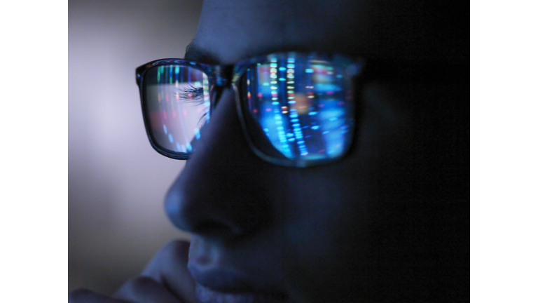 Genetic research, computer screen reflection in spectacles of DNA profile, close up of face