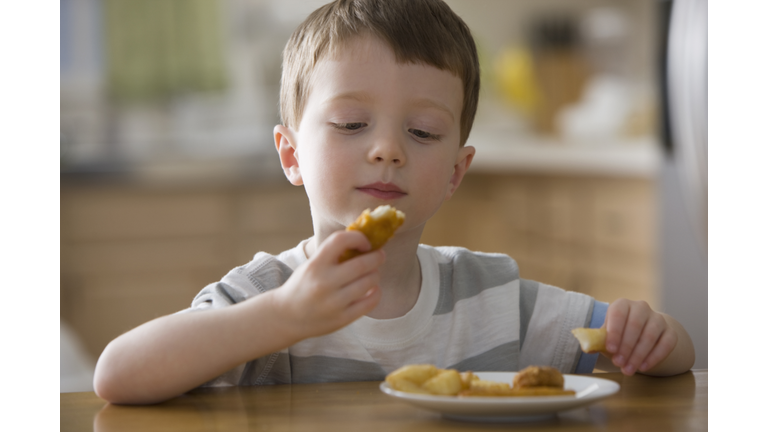 Caucasian boy eating chicken nuggets