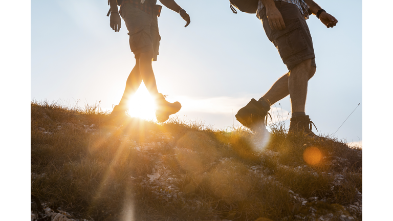 Italy, Monte Nerone, close-up of two men hiking in mountains at sunset