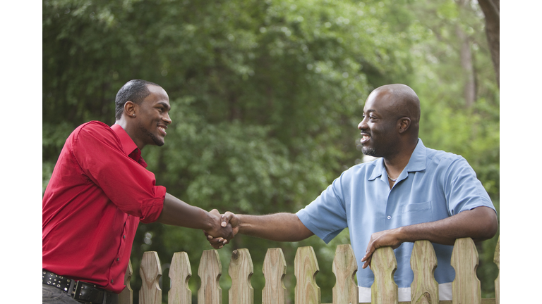 African American neighbors greeting each other over fence