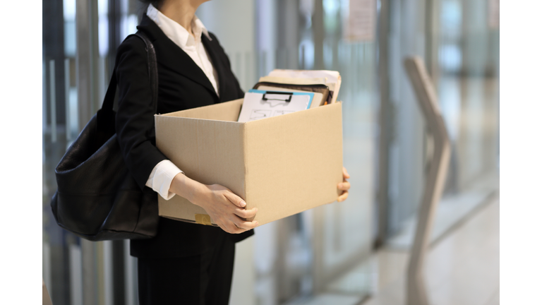 Businesswoman leaving office with box of personal items