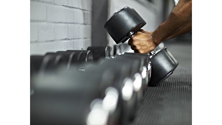 Athletic Male Picking Up Dumbbells in Gym