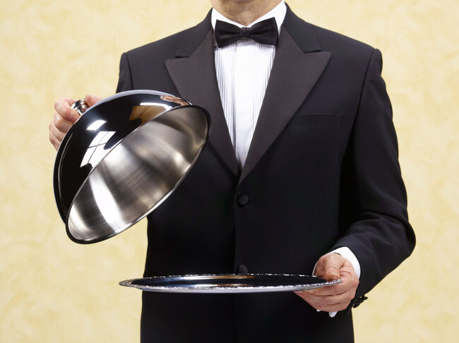 Butler waiter holding open domed silver tray.