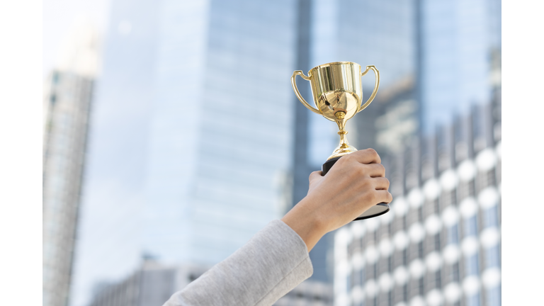 Business goals,Business concept.Close up hand of businesswoman holding gold trophy.