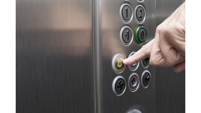 Forefinger pressing the alarm button in the elevator