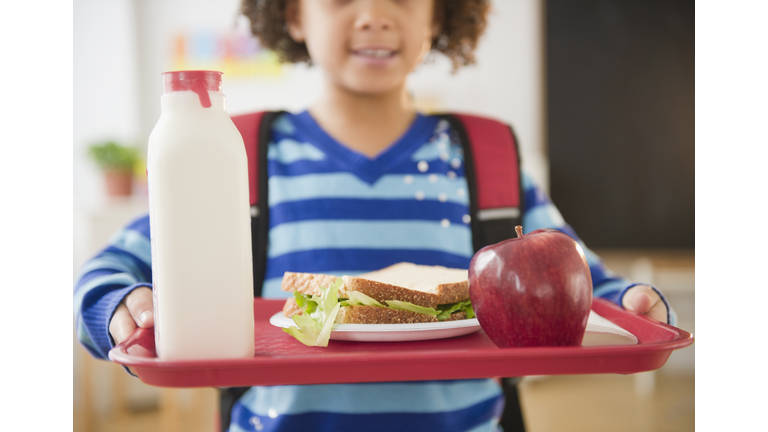 African American school girl holding lunch on a tray