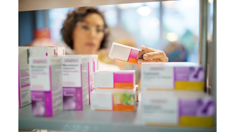 Female pharmacist checking medicines on rack