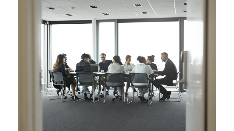 Co-workers having meeting with laptop in conference room