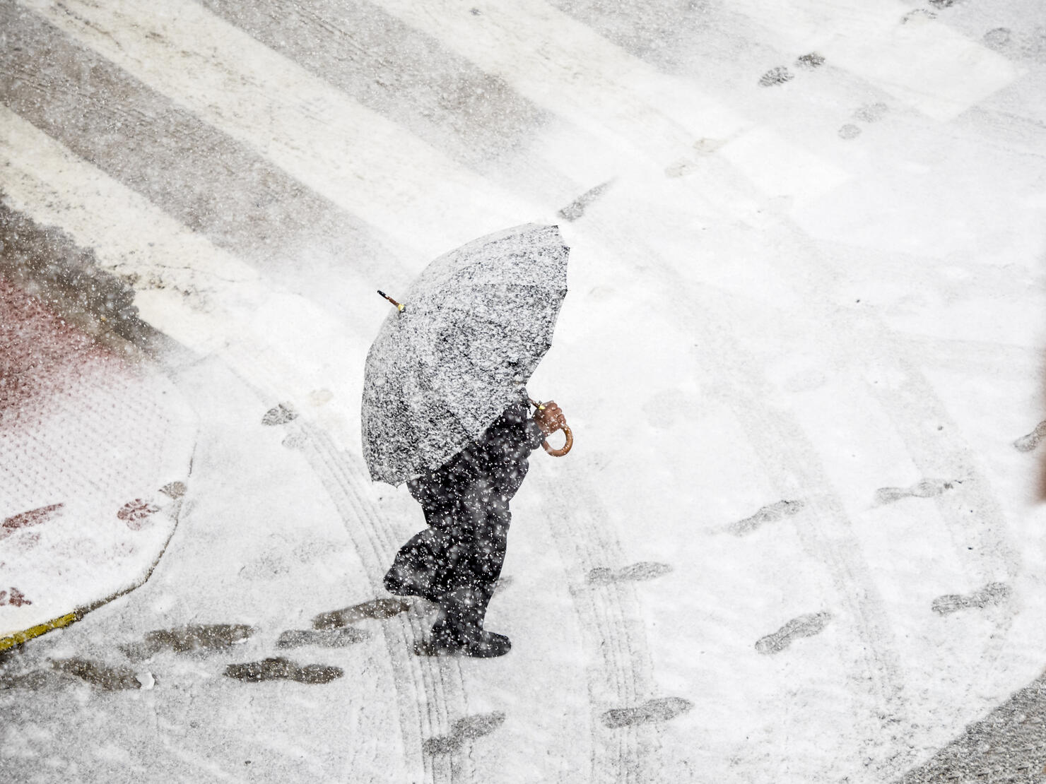 High angle view of person with umbrella walking in snow on street  with red umbrella in snowstorm. Valencia, Spain