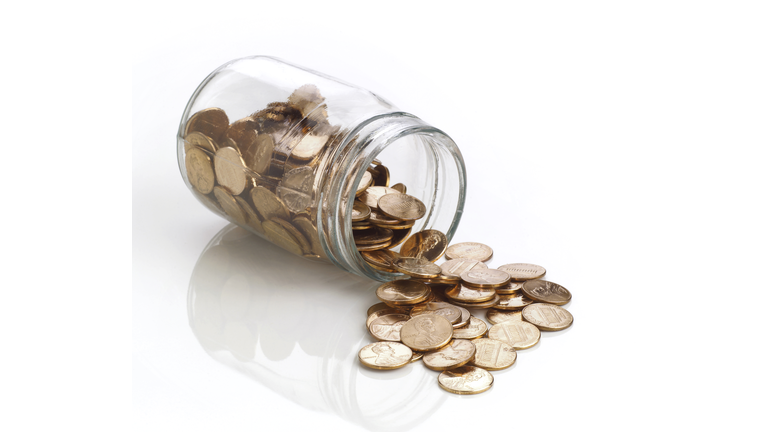 Jar of polished US pennies spilling out on white