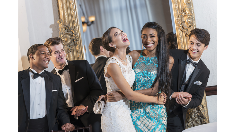 Teenagers in gowns and tuxedos at formal party