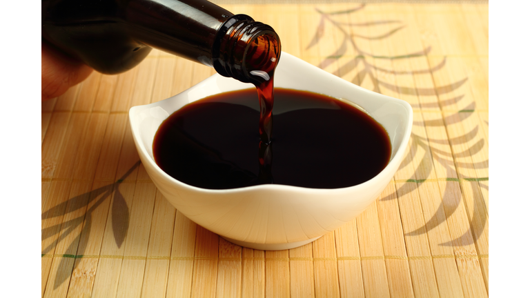 Pouring soy sauce into a white bowl