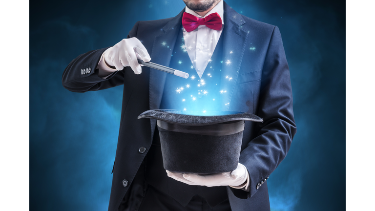 Magician or illusionist is showing magic trick. Blue stage light in background.
