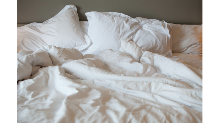 A messy bed with comforter and pillows