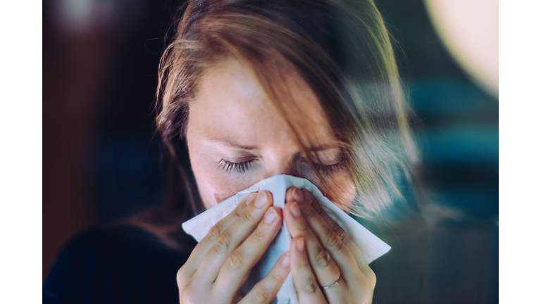 Woman sneezing behind a window.