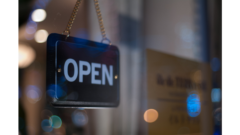 Close-Up Of Open Sign Hanging From Glass Window Of Store