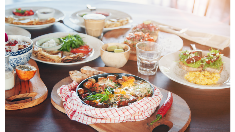 Brunch table with various dishes - fried eggs, crepes and tapas