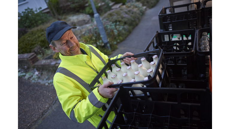 Milkman unloading his milk float in early morning