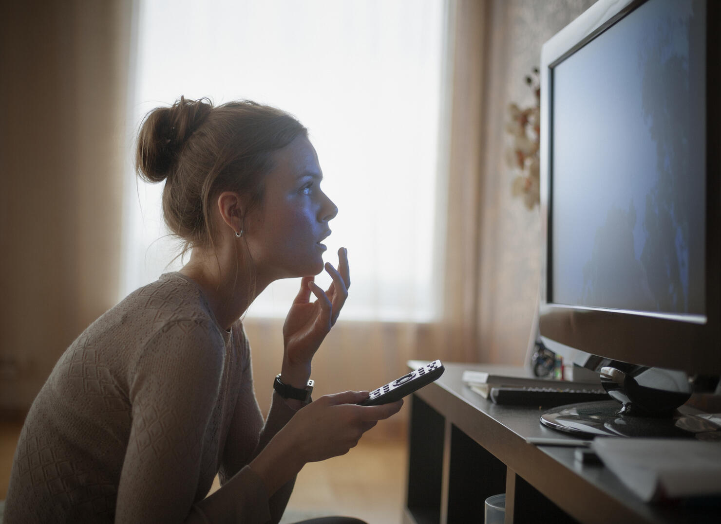 young woman looking in suspense at tv