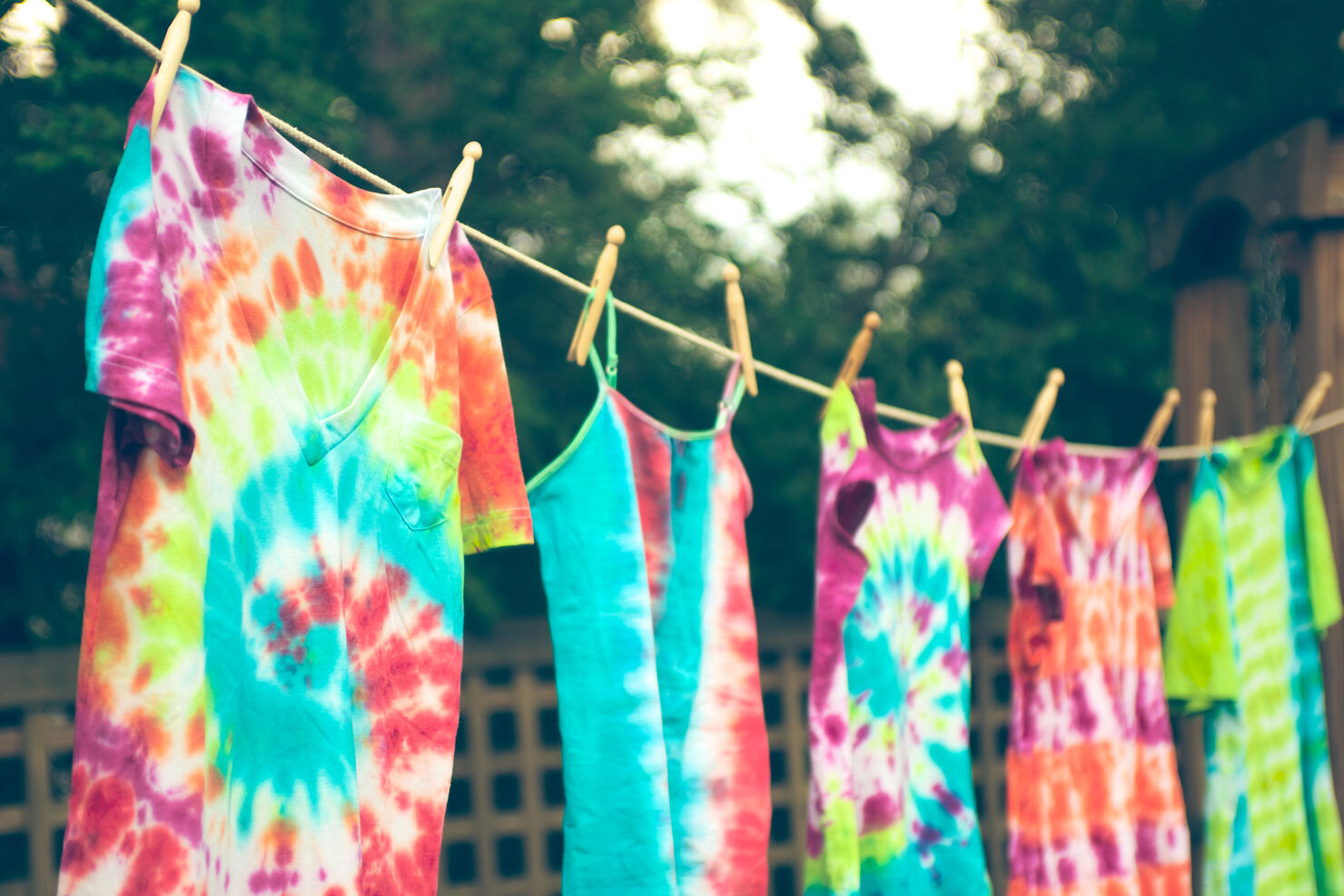 Tie dyed tee shirts hanging from a clothes line.