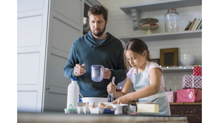 Father and daughter baking at table in kitchen