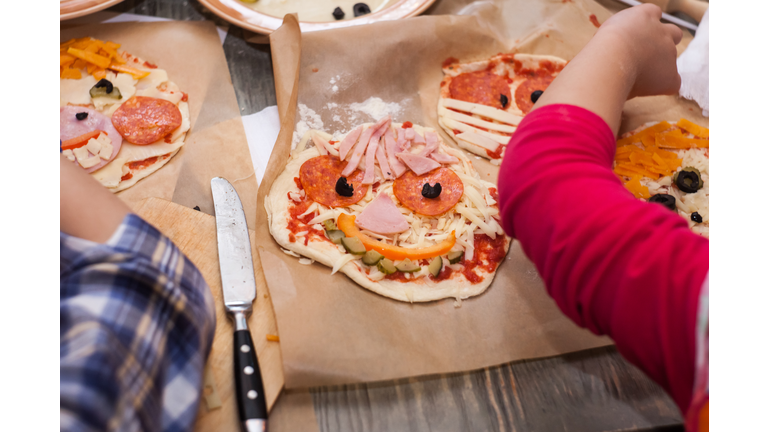 Master class for children on baking funny halloween pizza. Young children learn to cook a funny monster pizza. Kids preparing homemade piizza. Little cook.