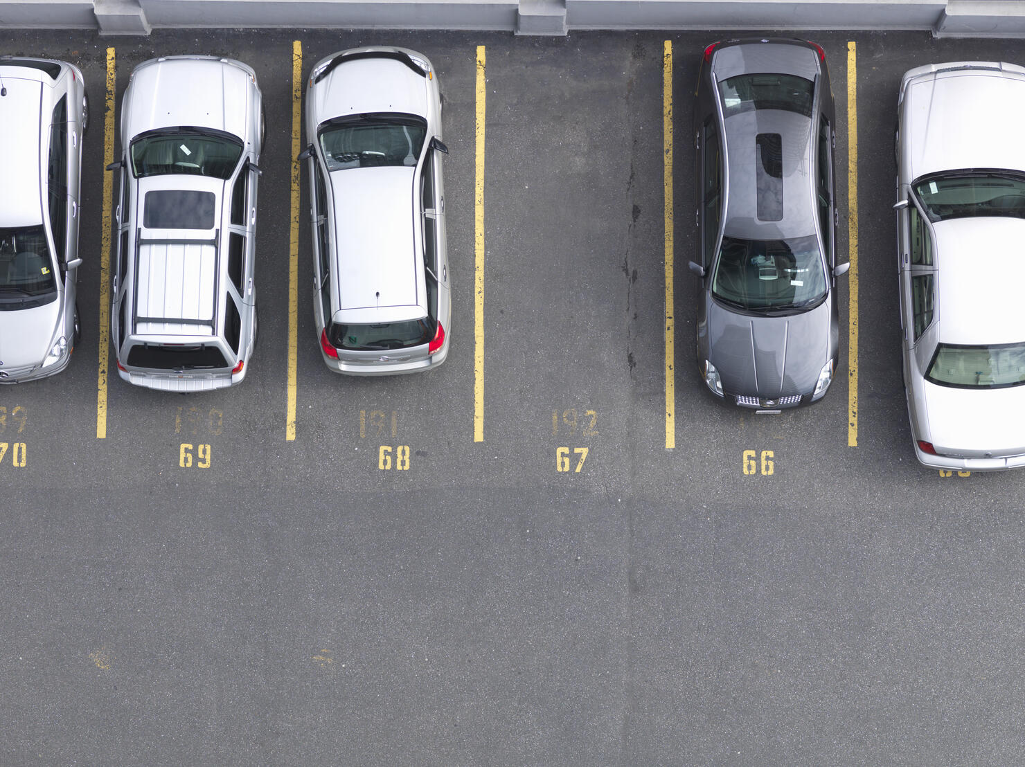 Overhead view of cars in parking lot, one empty 