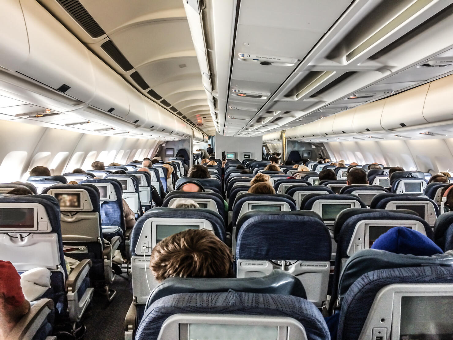 Inside of plane seen from rear with passengers
