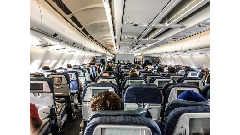 Inside of plane seen from rear with passengers