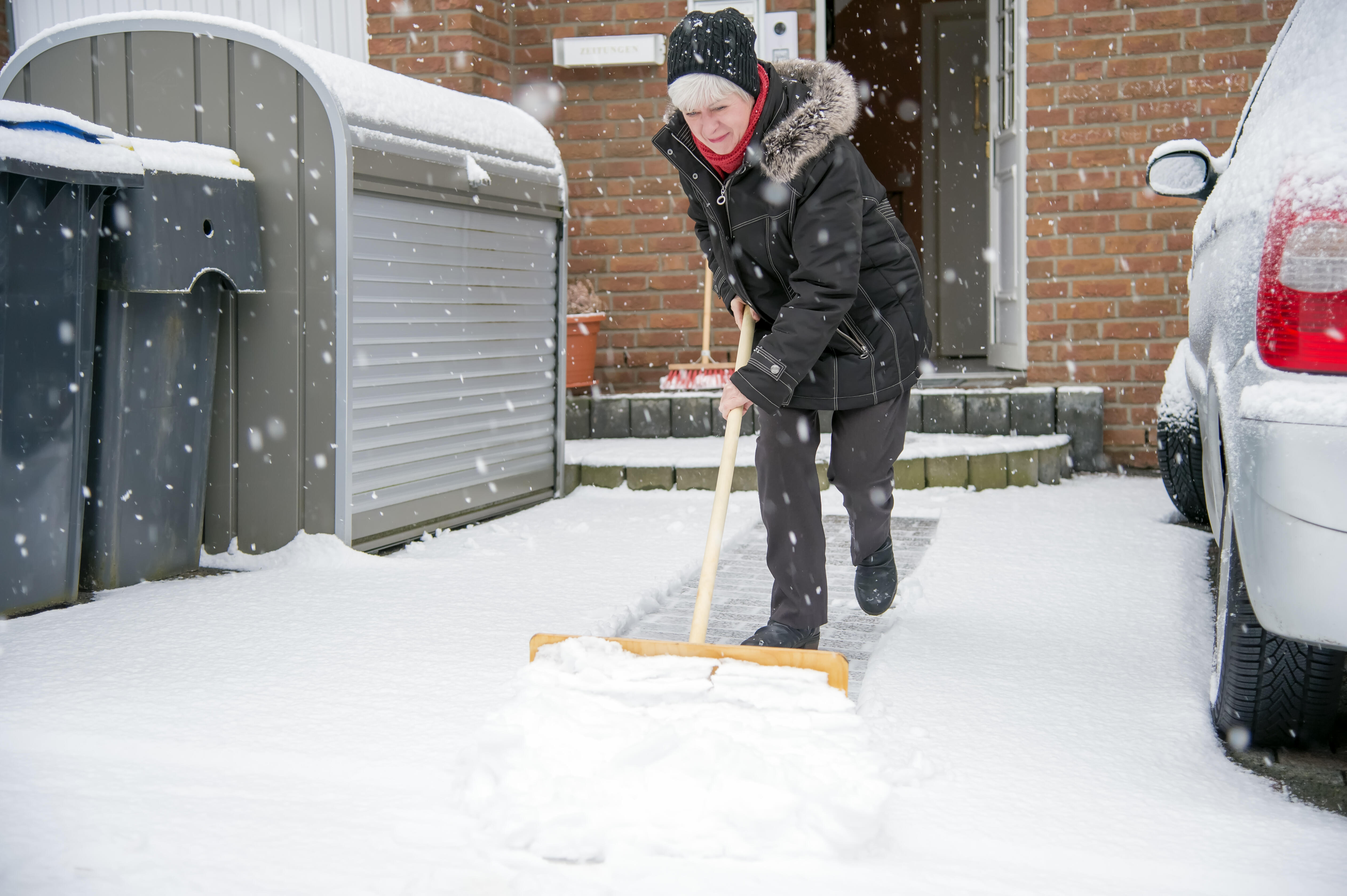 Прийти неожиданно дорожки не расчищены. Женщина убирает снег. Зимняя лопата. Убирает снег лопатой. Чистильщик снега.