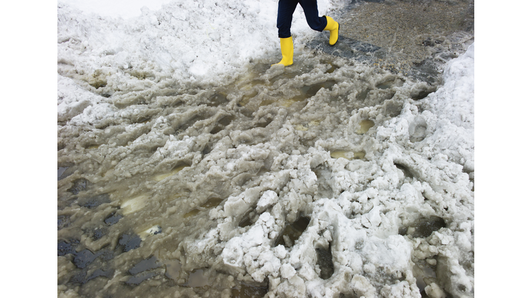 USA, New York, New York City, legs of person in yellow rubber boots walking in slush