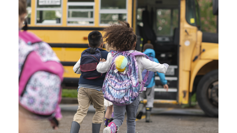 Diverse group of happy children getting on school bus