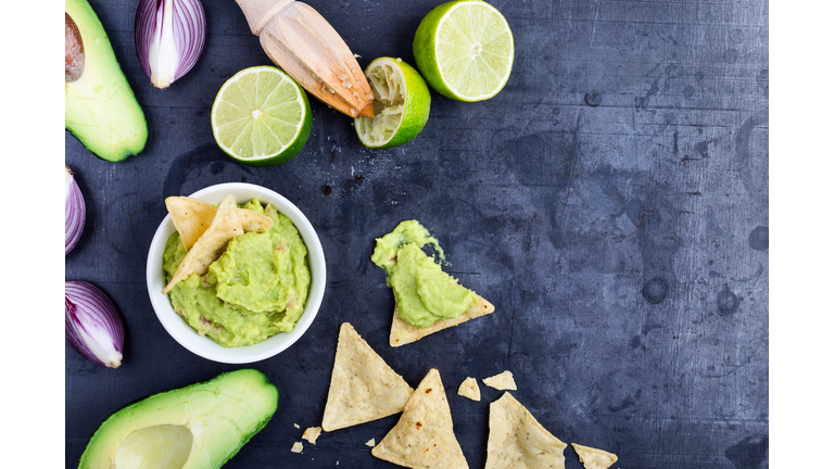 Homemade avocado guacamole dip with fresh ingredients on gark grey background with copy space