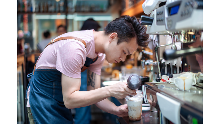 Asian Barista making coffee in the cafe