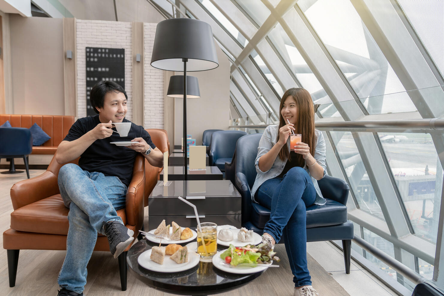Asian couple sitting and eatting inn airport lounge when waiting the flight at modern international airport