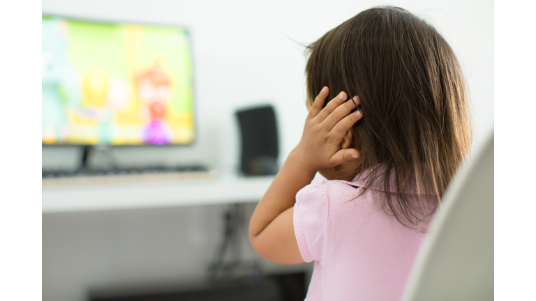 A terrified child, afraid of the loud sounds from the television. Autism.