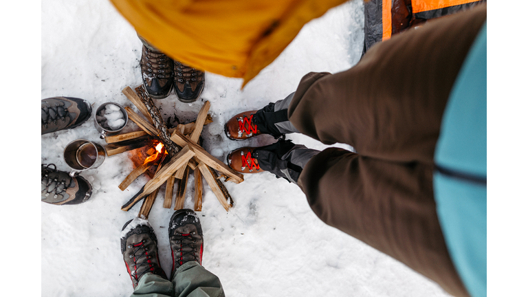 Tourists warming by campfire on snow