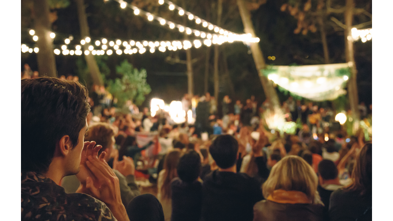Young man clapping in night music festival