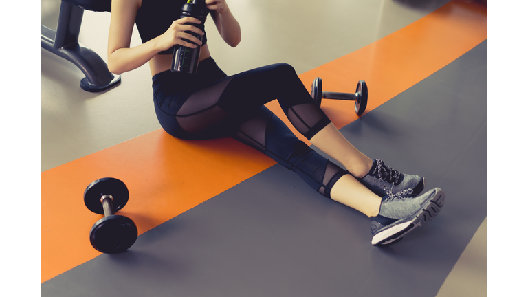 Low Section Of Woman Holding Water Bottle In Gym