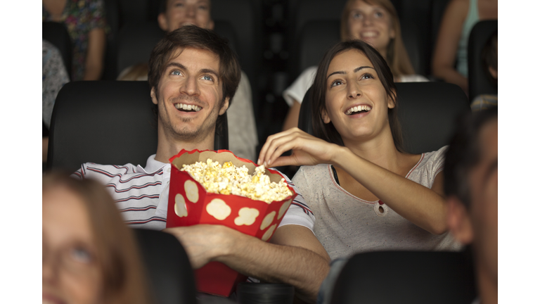 Couple eating popcorn in movie theater