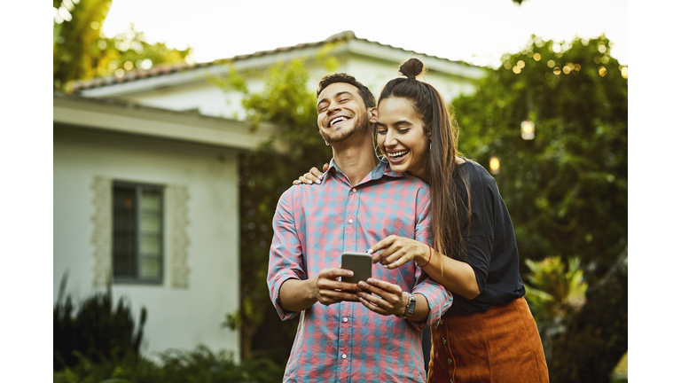 Happy couple looking at smart phone in back yard